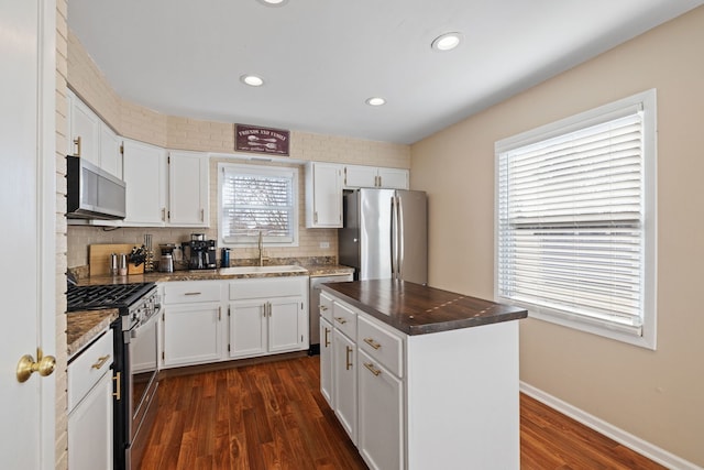 kitchen featuring dark wood-style floors, white cabinets, stainless steel appliances, and a sink