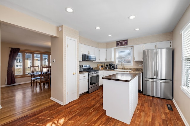 kitchen featuring a sink, decorative backsplash, dark wood finished floors, and stainless steel appliances