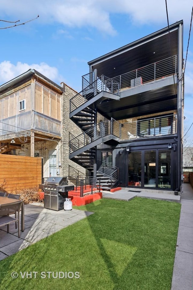 back of house featuring stairway, fence, and a lawn
