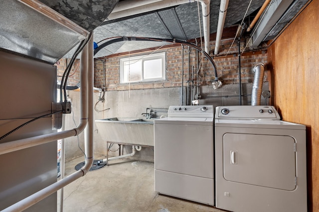 clothes washing area with a sink, independent washer and dryer, and laundry area