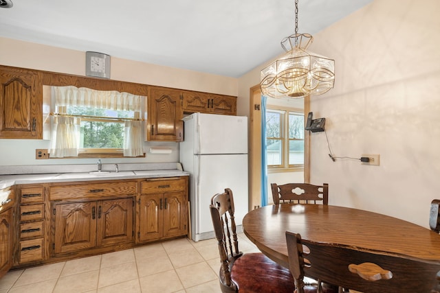 kitchen featuring light countertops, brown cabinetry, freestanding refrigerator, and a sink