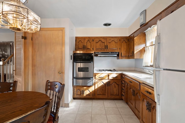 kitchen featuring white appliances, a sink, light countertops, under cabinet range hood, and a warming drawer