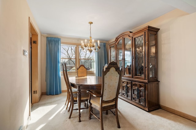 dining area with a chandelier, light colored carpet, and baseboards