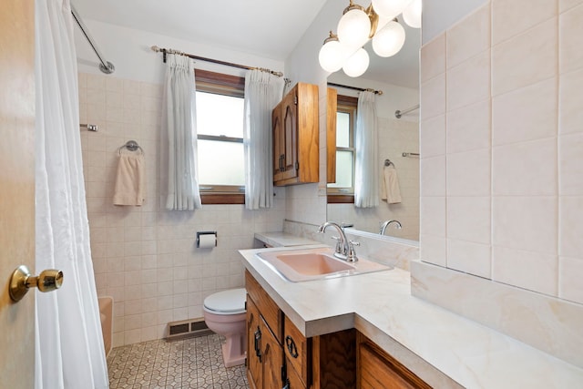 bathroom with visible vents, toilet, tile walls, tile patterned flooring, and vanity