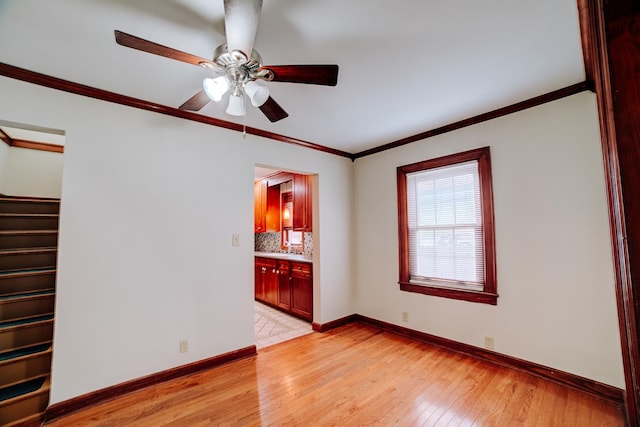 319 S 3rd St, Watseka, IL 60970 - empty room with light wood finished floors, crown molding, baseboards, ceiling fan, and stairway