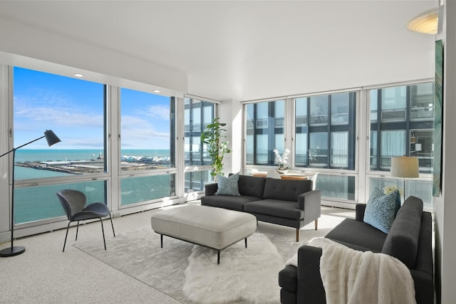 carpeted living area with a baseboard radiator, a water view, and expansive windows