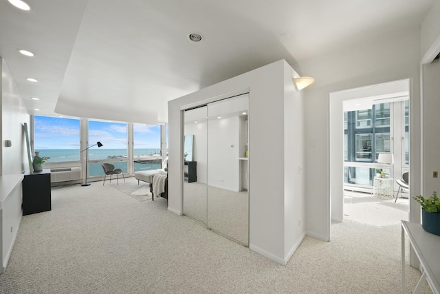 hall with a wall of windows, carpet, baseboards, recessed lighting, and a water view