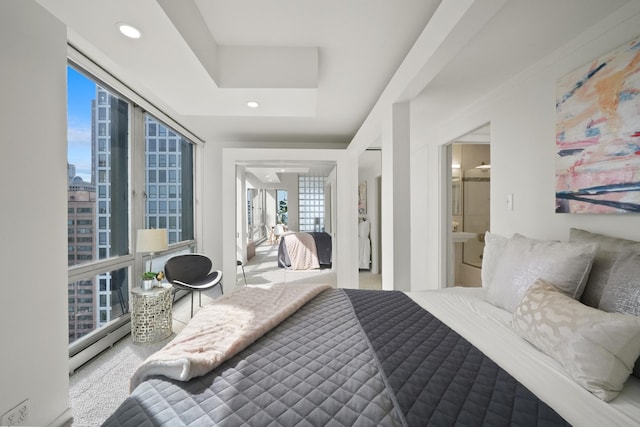 bedroom with recessed lighting, a baseboard radiator, a raised ceiling, and connected bathroom