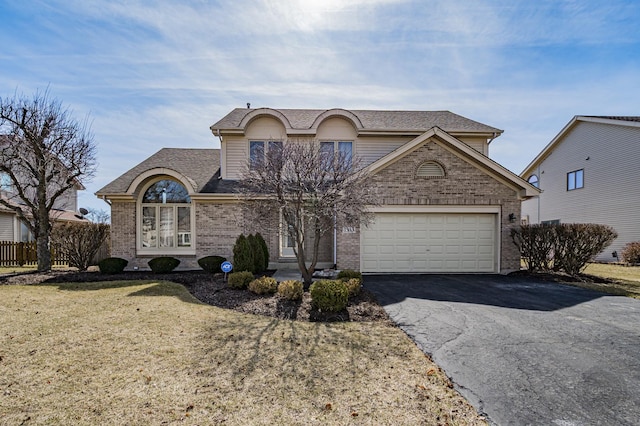 traditional-style house featuring brick siding, fence, a front yard, a garage, and driveway