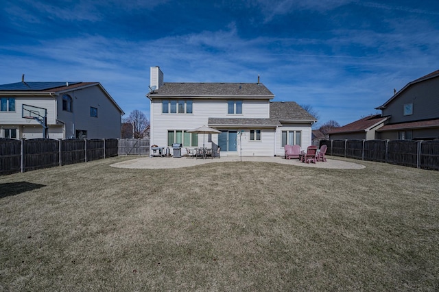 back of property featuring a patio, a lawn, a fenced backyard, and a chimney