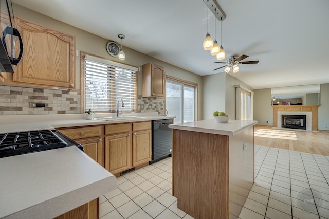 kitchen featuring black appliances, a sink, a center island, light tile patterned floors, and ceiling fan