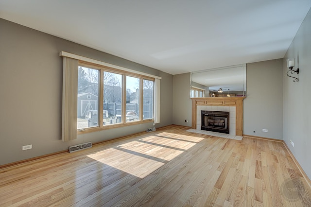 unfurnished living room with visible vents, baseboards, light wood-style floors, and a tile fireplace