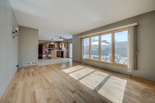 unfurnished living room featuring baseboards, visible vents, and light wood-type flooring