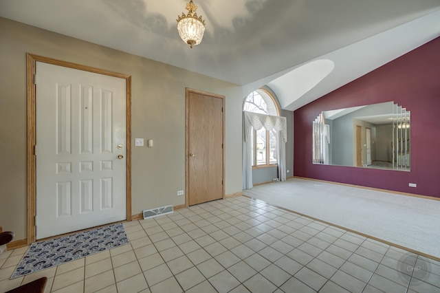 foyer with visible vents, a chandelier, vaulted ceiling, light carpet, and light tile patterned floors