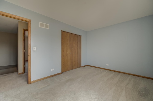 unfurnished bedroom featuring light carpet, visible vents, baseboards, and a closet