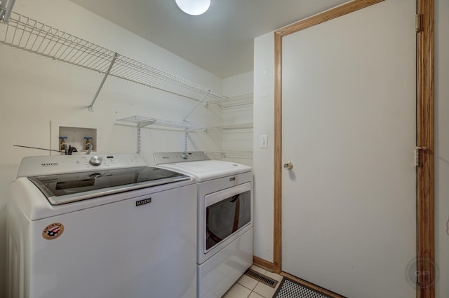 laundry area featuring washer and dryer, laundry area, and light tile patterned floors