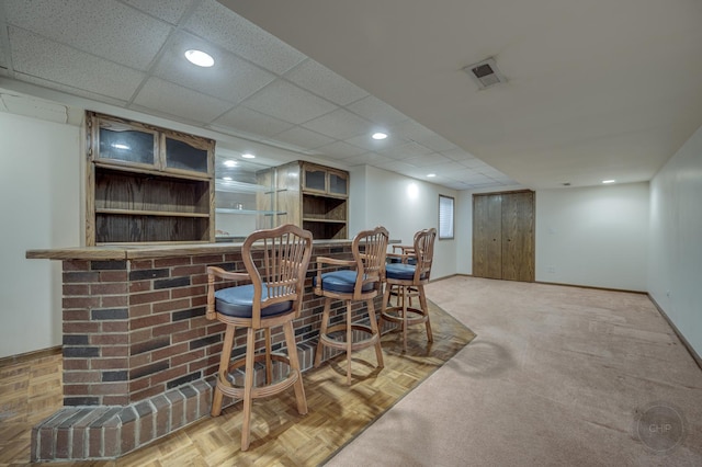 bar featuring a bar, visible vents, baseboards, and a paneled ceiling