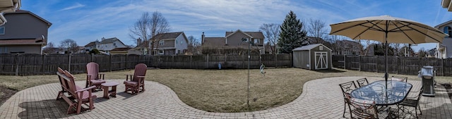 view of patio featuring a storage shed, an outdoor structure, a fenced backyard, and a residential view