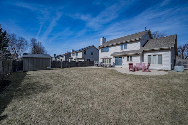 back of house with a yard, a fenced backyard, a patio area, a storage unit, and an outbuilding