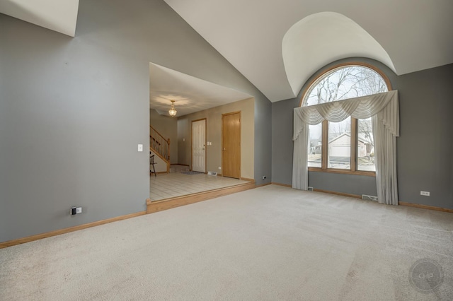 carpeted empty room with stairway, high vaulted ceiling, and baseboards