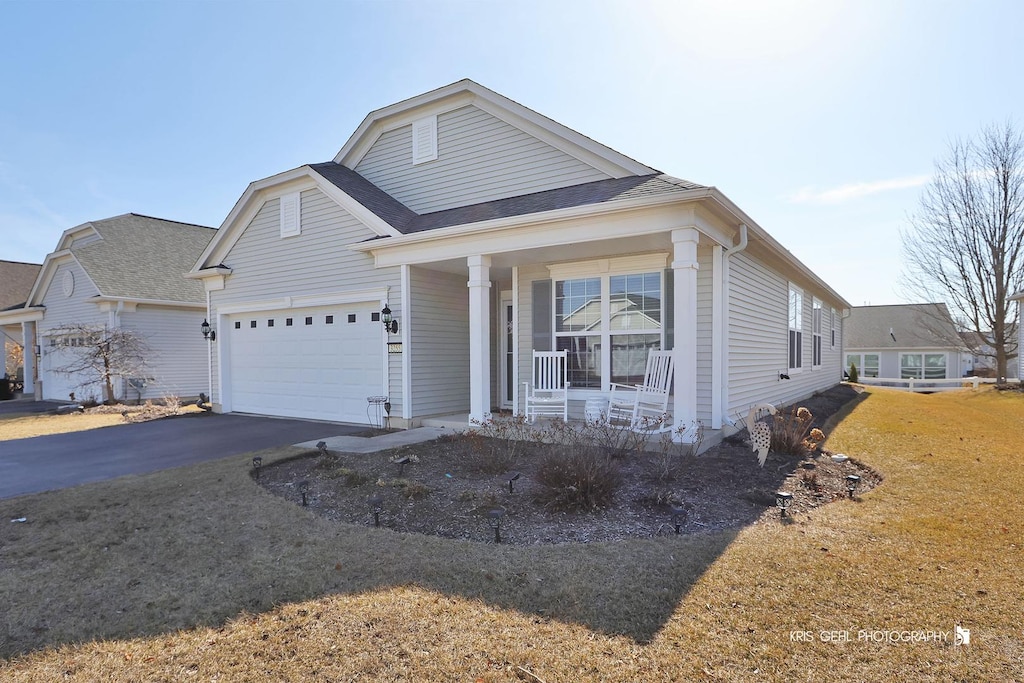view of front of home featuring driveway, a porch, roof with shingles, a front yard, and an attached garage