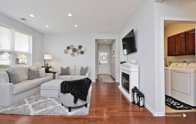 living area featuring visible vents, dark wood-type flooring, recessed lighting, baseboards, and washing machine and clothes dryer