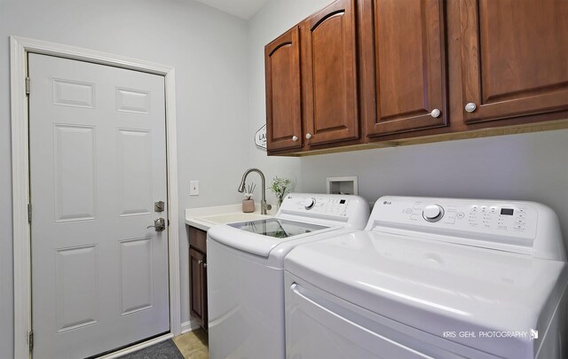 washroom featuring washing machine and clothes dryer, cabinet space, and a sink