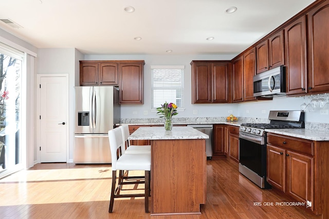 kitchen with a kitchen bar, light wood-style floors, a kitchen island, and stainless steel appliances