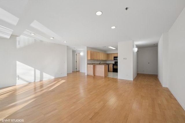 unfurnished living room with light wood-style flooring, recessed lighting, baseboards, and a sink