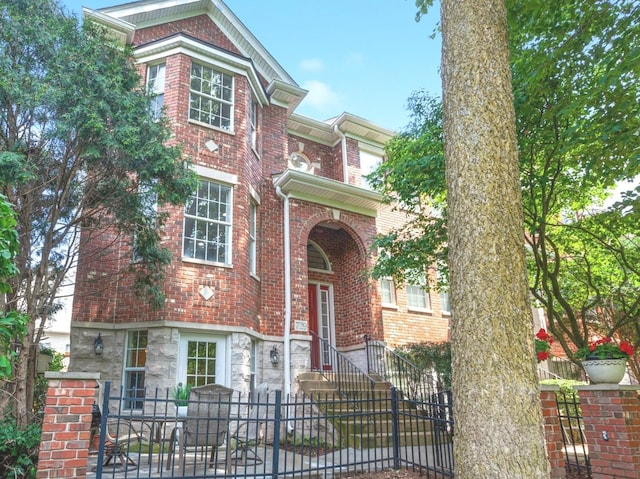 view of front of home featuring brick siding, stone siding, and a fenced front yard