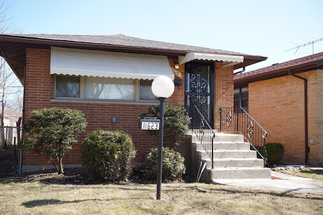 view of front of property featuring brick siding and roof with shingles