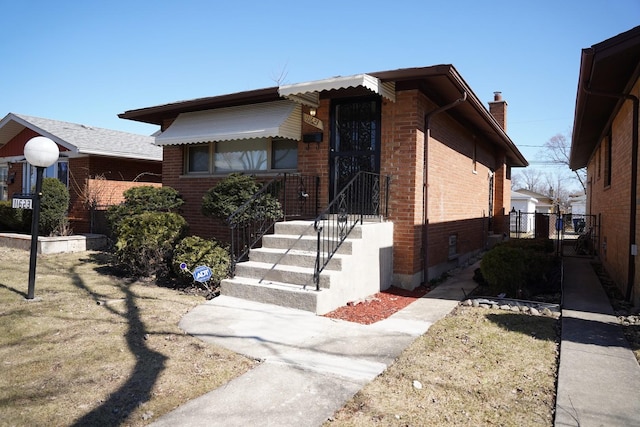 view of front of home featuring fence, brick siding, and a chimney