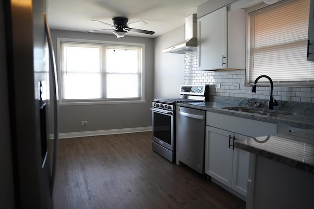 kitchen with dark wood-style floors, a sink, decorative backsplash, appliances with stainless steel finishes, and wall chimney exhaust hood