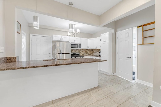 216 W 105th St, Chicago, IL 60628 - kitchen with dark stone counters, a peninsula, a sink, white cabinets, and appliances with stainless steel finishes