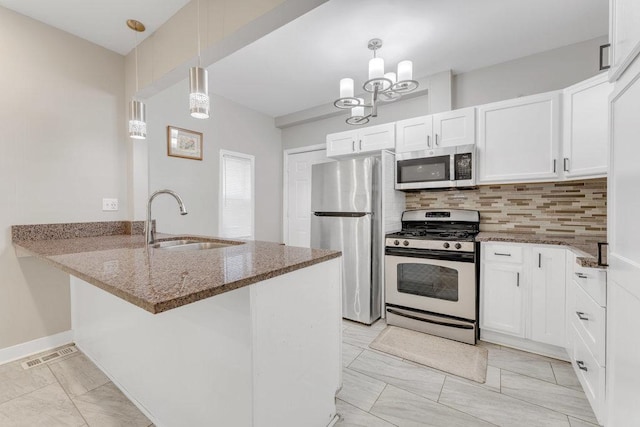 216 W 105th St, Chicago, IL 60628 - kitchen featuring dark stone countertops, a peninsula, a sink, white cabinets, and appliances with stainless steel finishes