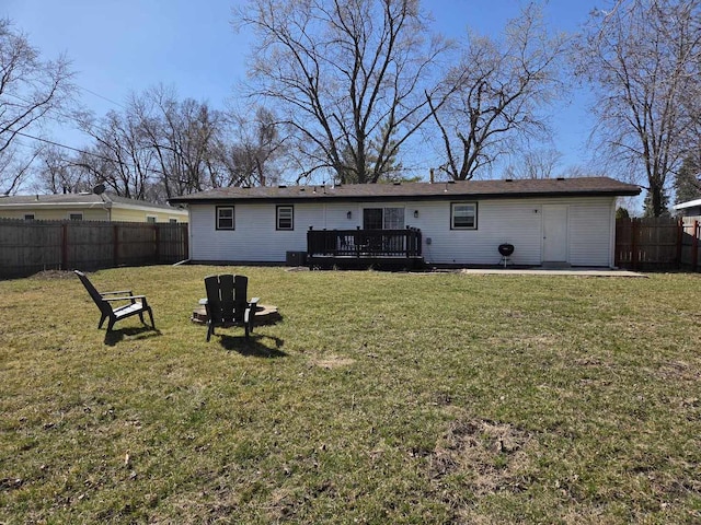 rear view of property featuring a wooden deck, a lawn, and fence