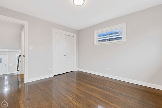 unfurnished bedroom with baseboards, dark wood-style flooring, and a closet