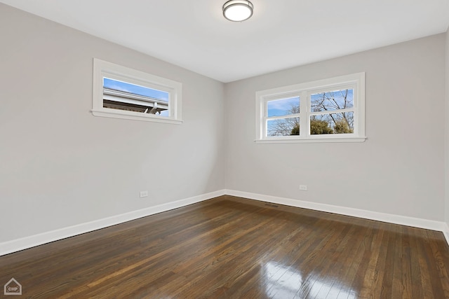 spare room with baseboards and dark wood-type flooring