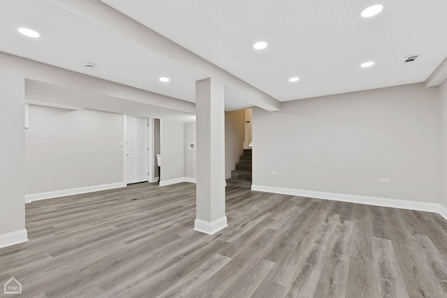 finished basement featuring stairway, recessed lighting, light wood-style floors, and baseboards