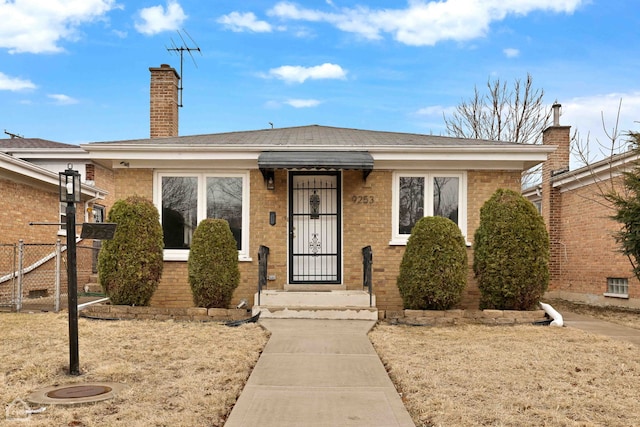 bungalow-style house with brick siding, a chimney, and fence