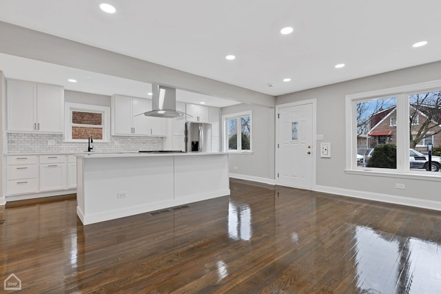 kitchen with visible vents, tasteful backsplash, stainless steel fridge, wall chimney range hood, and baseboards