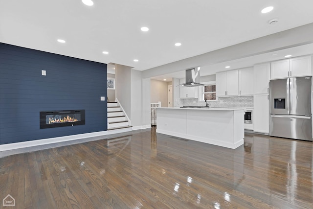 kitchen with ventilation hood, stainless steel fridge, white cabinets, a fireplace, and decorative backsplash