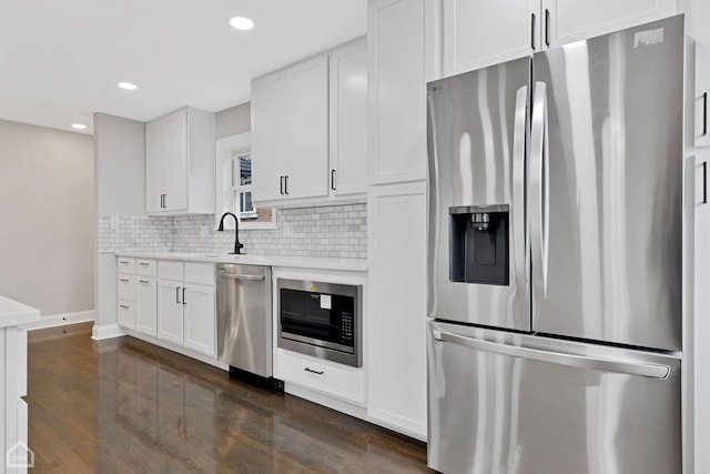 kitchen with backsplash, light countertops, stainless steel appliances, white cabinetry, and a sink