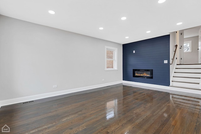 unfurnished living room with plenty of natural light, recessed lighting, a fireplace, and baseboards