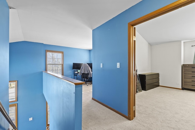 corridor featuring lofted ceiling, an upstairs landing, carpet, and baseboards