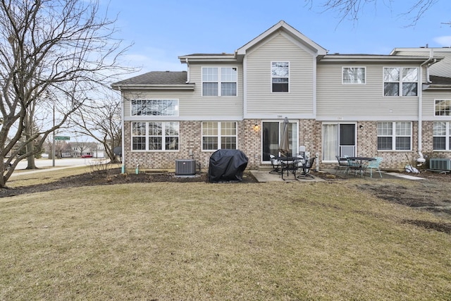 rear view of property featuring cooling unit, brick siding, and a yard