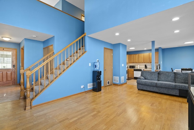 living room featuring light wood finished floors, visible vents, baseboards, stairway, and recessed lighting