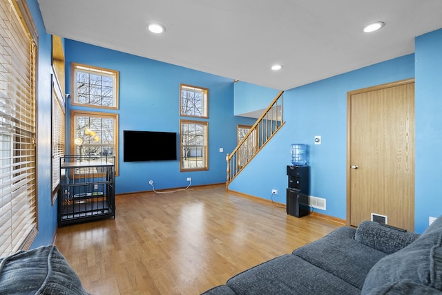 living area featuring plenty of natural light, stairs, baseboards, and wood finished floors