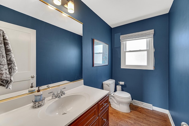 bathroom featuring visible vents, toilet, wood finished floors, baseboards, and vanity