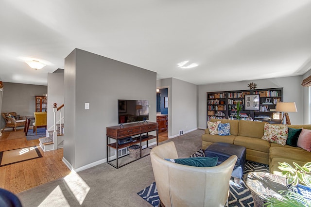 living area featuring baseboards, light carpet, and stairs